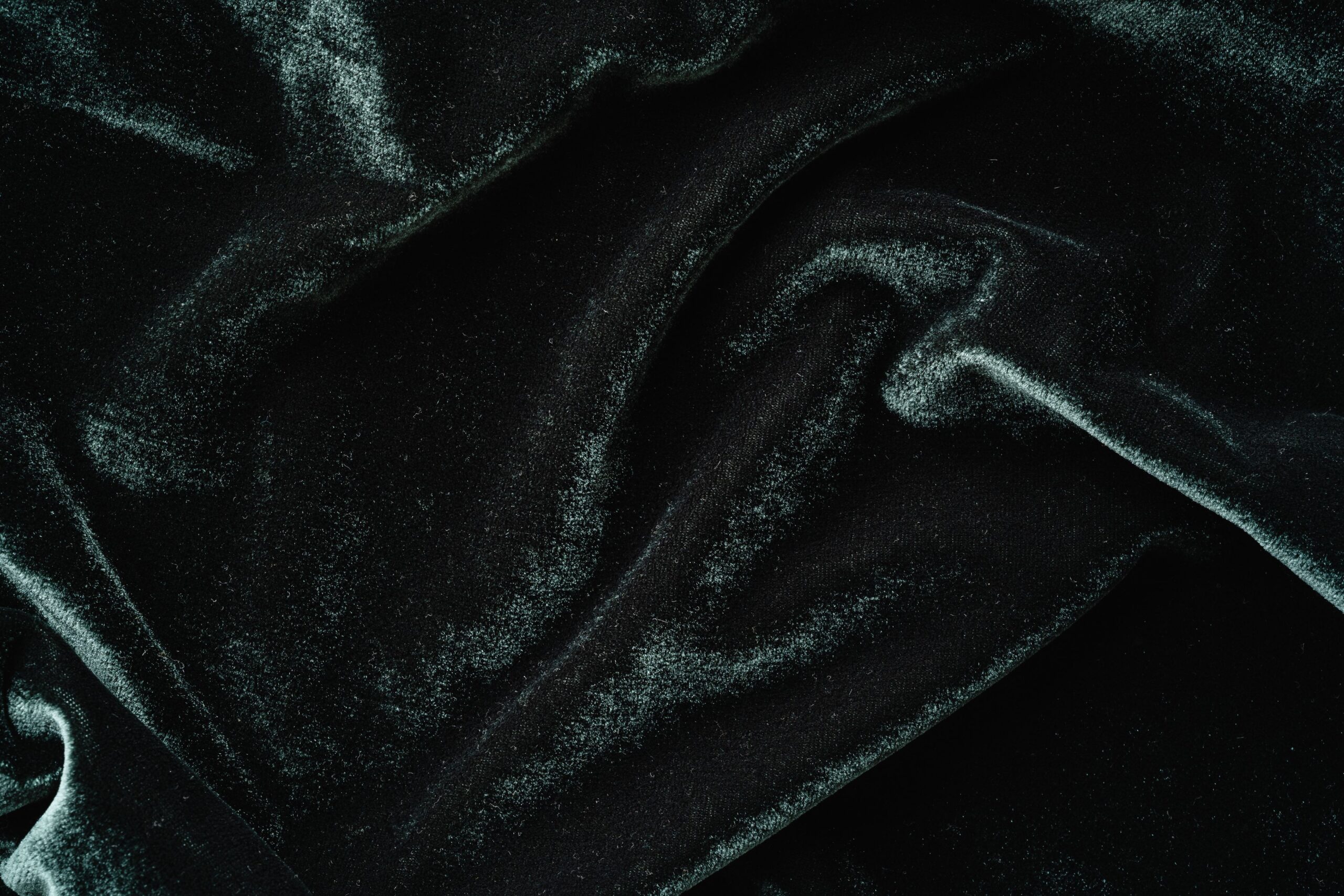 Rich textured black velvet fabric in close-up, showcasing soft folds and sheen.